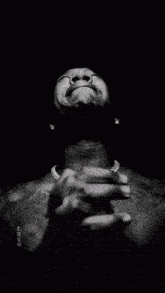 a black and white photo of a man with his hands folded in front of his face