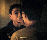 a man covering his mouth with his hand and another man says i 'm here