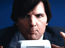 a man in a suit and tie holds a white object in his mouth