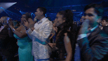 a man in a suit and bow tie is applauding in a crowd of people