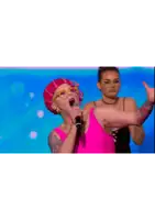 a woman singing into a microphone while another woman looks on