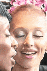 a woman with a flower crown on her head is being kissed by another woman