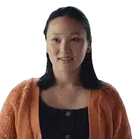 a woman wearing an orange cardigan and a black top is smiling