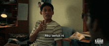 a man is sitting on a couch with the words aku serius ni written on the bottom