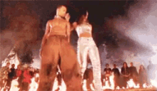 a man and a woman are dancing in front of a crowd of people in front of a fire .