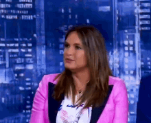 a woman in a pink jacket is sitting in front of a cityscape