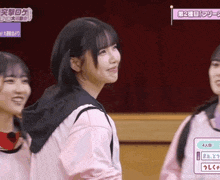 a girl in a pink shirt is smiling while standing next to another girl