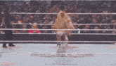 two women are wrestling in a ring with a crowd behind them