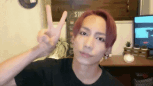 a young man with red hair is giving the peace sign