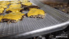 a bunch of cheeseburgers are on a metal tray that says made in animotica