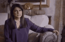 a woman in a purple shirt is sitting on a white couch .
