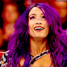 a woman with purple hair is smiling and looking up