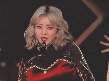 a woman singing into a microphone while wearing a red top