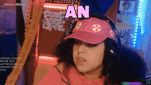 a woman wearing headphones and a pink hat says an on the screen