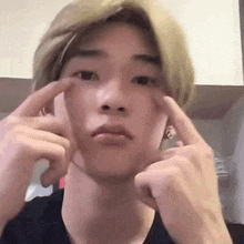 a young man is making a funny face with his fingers .
