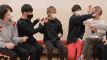 a group of young men wearing masks are sitting in a circle