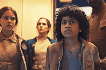 a young boy with curly hair is wearing a jacket with the letter s on it