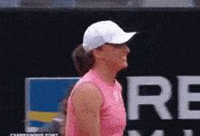 a woman wearing a white hat and a pink tank top is standing in front of a sign that says championship point