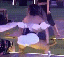 a woman is doing a trick on a stage while a man stands behind her .