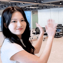 a woman with long black hair is clapping her hands in a room