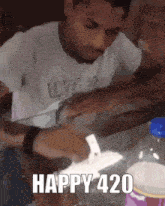 a man is sitting at a table with a bottle of soda in front of him and smoking a cigarette .