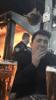 a man sitting at a table with two glasses of beer and a sign that says no dogs allowed
