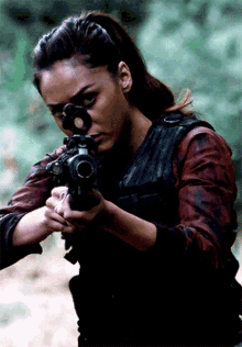 a woman with a ponytail is holding a gun with a scope on it