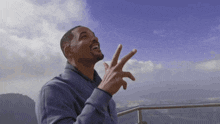 a man making a peace sign with his fingers in front of a cloudy sky