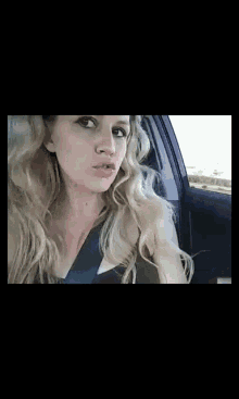 a woman is sitting in a car looking out the window .