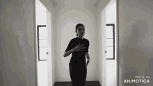 a woman in a black shirt is standing in a hallway with the words made in animotica on the bottom