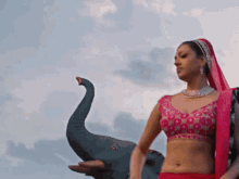 a woman in a pink top is standing in front of a statue of an elephant