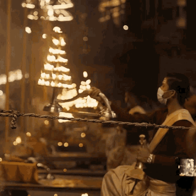 a man wearing a mask is holding a candle in front of a candle tower