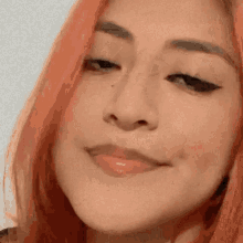 a close up of a woman 's face with red hair making a face .