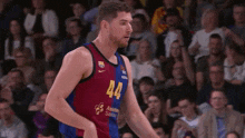 a basketball player with the number 44 on his jersey stands in front of a crowd