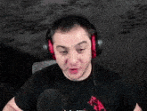 a man wearing headphones is making a funny face while talking into a microphone .