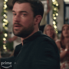 a man with a beard is wearing a black shirt with an amazon prime logo in the corner