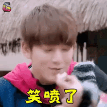a young man is holding a small animal in his hands and making a face .