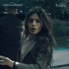 a woman in a suit stands in front of a sign that says hulu