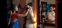 a woman is putting flowers in another woman 's hair in front of a mirror