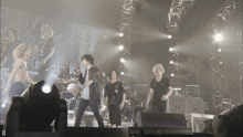 a group of people on a stage with the letter d on the bottom left