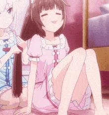 a girl in a pink dress is sitting on the floor with another girl brushing her hair