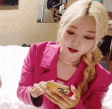 a woman in a pink jacket is looking at her phone .