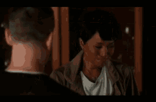 a man and a woman are looking at each other in a room . the woman is crying and the man is smiling .