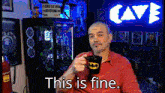 a man in a red shirt is holding a batman mug with the words this is fine below him