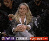 a woman sits in the stands watching a basketball game