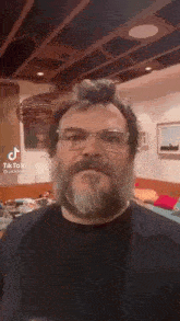 a man with a beard and glasses is making a funny face .