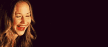 a close up of a woman 's face with a black background and a smile on her face .