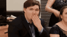 a man in a suit and tie is covering his mouth
