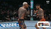 two fighters are fighting in a cage with a bud light sign in the background