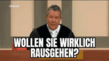 a man in a judge 's robe is sitting in front of a sign that says " wollen sie wirklich rausgehen "